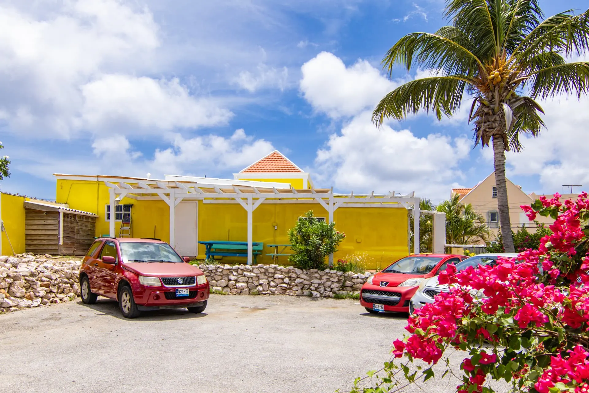 Casa 2 exterior parking area with palm tree and colorful flowers