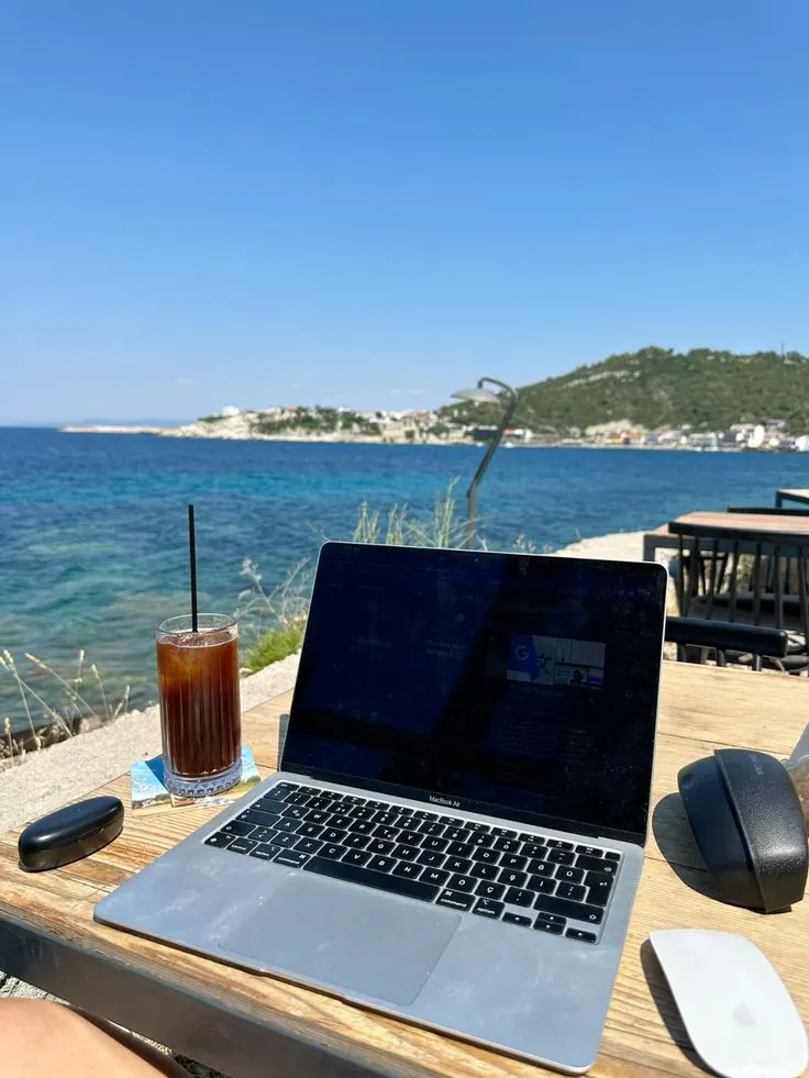 Student working on a laptop by the sea during an internship in Curaçao