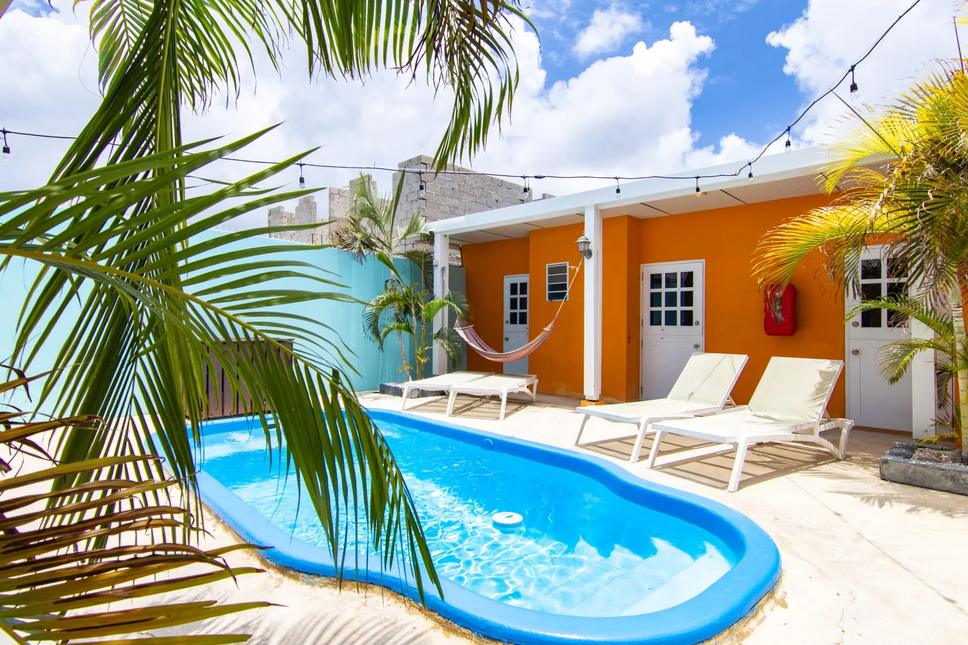 Casa 7 pool with sun loungers, hammock, and string lights