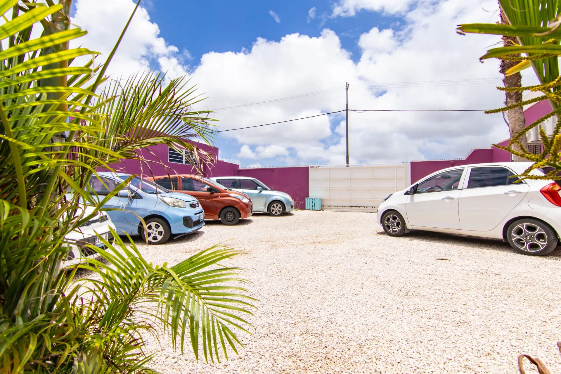 Casa 7 secure parking area with colorful buildings and palm trees