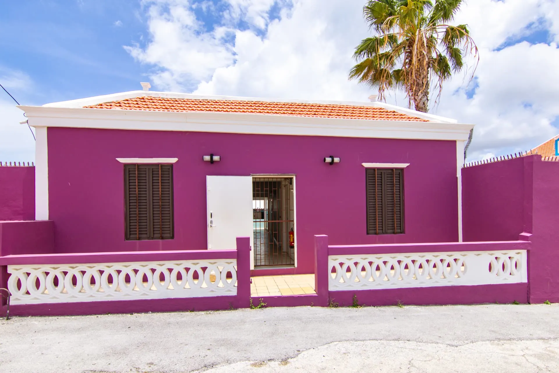 Casa 7 purple exterior with palm tree and blue sky